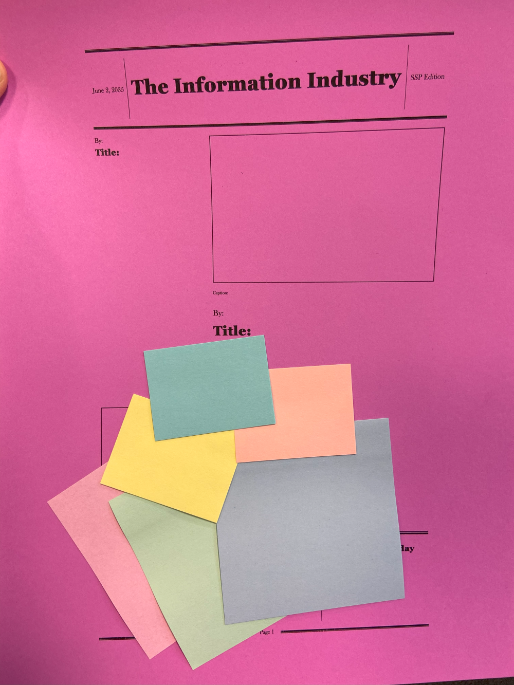 A large pink sheet of paper titled “The Information Industry” with blank sections below to be filled with text and images, with smaller, colorful squares of paper stacked on top.