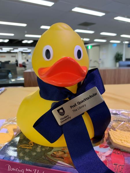 A rubber duck wearing a ribbon around its neck with a name badge identifying the duck as Professor Quacktackular of the Flinders University library