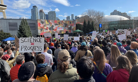 A photograph of a crowd of people at the Stand Up For Science protest in Seattle, Washington on 07 March 2025. Many people are holding signs, one of which says 