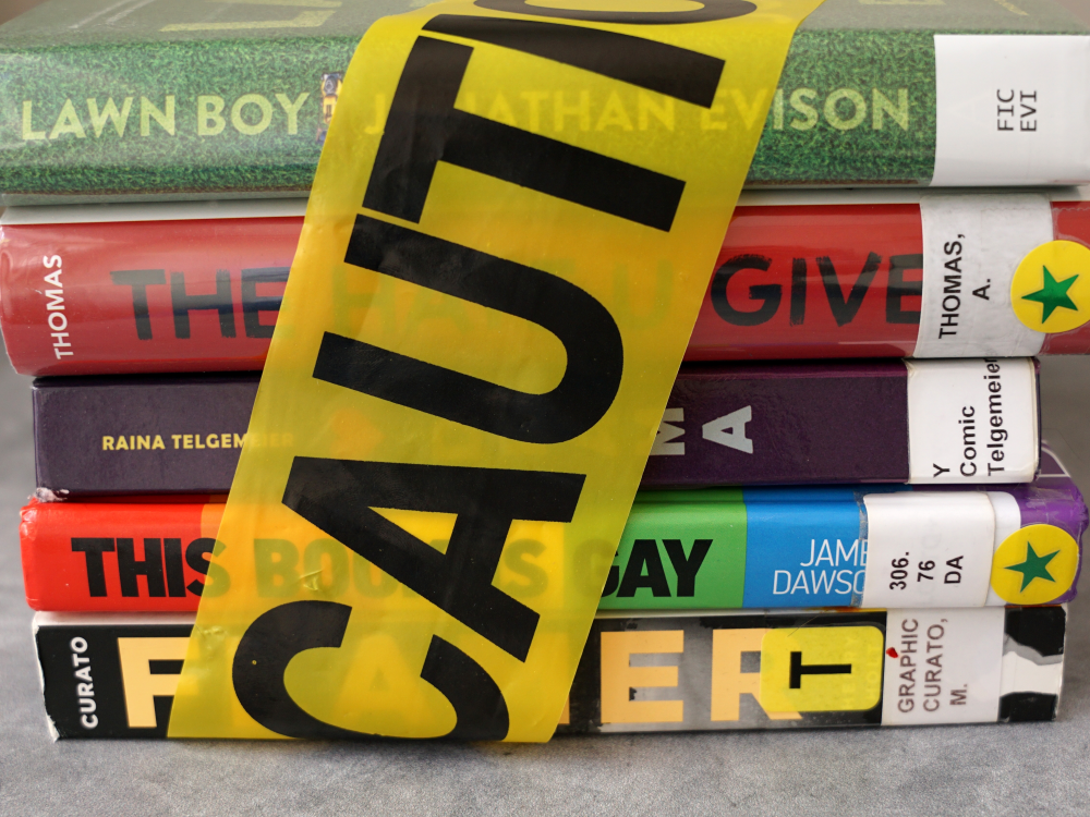 A stack of books found on frequently banned book lists wrapped in caution tape