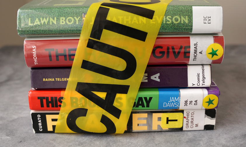 A stack of books found on frequently banned book lists wrapped in caution tape