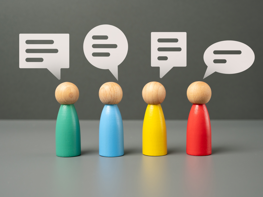 Four wooden figures communicating via speech bubbles