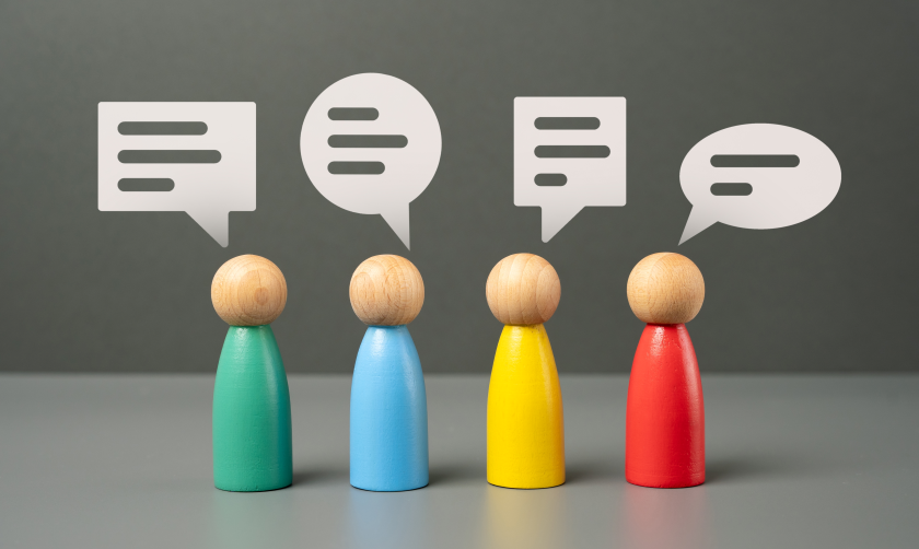 Four wooden figures communicating via speech bubbles