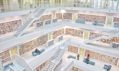 The interior of a library building with several floors lined with bookshelves, with exposed staircases, surrounding an open area