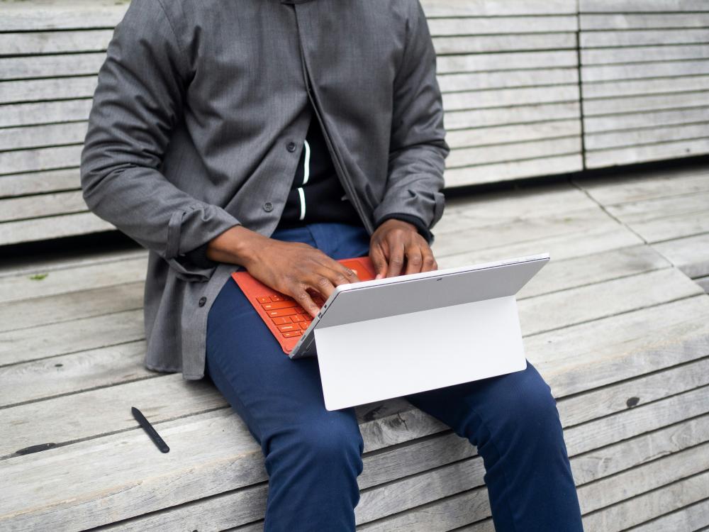 A man sitting on a bench using a laptop computer