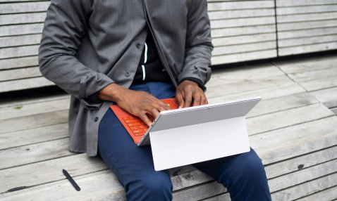 A man sitting on a bench using a laptop computer