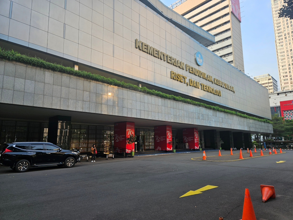 A long, low office building with a flat concrete front, labeled with the name, in Indonesian, of Indonesia’s office of the Ministry of Education and Culture