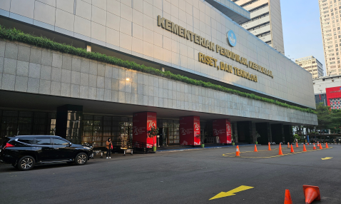 A long, low office building with a flat concrete front, labeled with the name, in Indonesian, of Indonesia’s office of the Ministry of Education and Culture